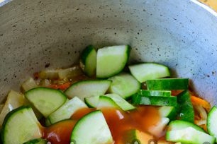 tilsett agurker og tomatpuré i pannen med løk og gulrøtter